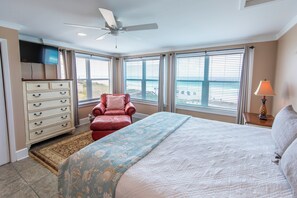 A bedroom with a bed, a red chair, a dresser, and a ceiling fan. - Sea Haunts 2A - Turtle Dunes! Community Pool, Gated neighborhood. (Santa Rosa Beach)