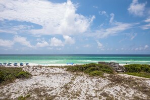 A beach with a wooden walkway leading to the water, surrounded by vegetation and beach chairs. - Sea Haunts 2A - Turtle Dunes! Community Pool, Gated neighborhood. (Santa Rosa Beach)