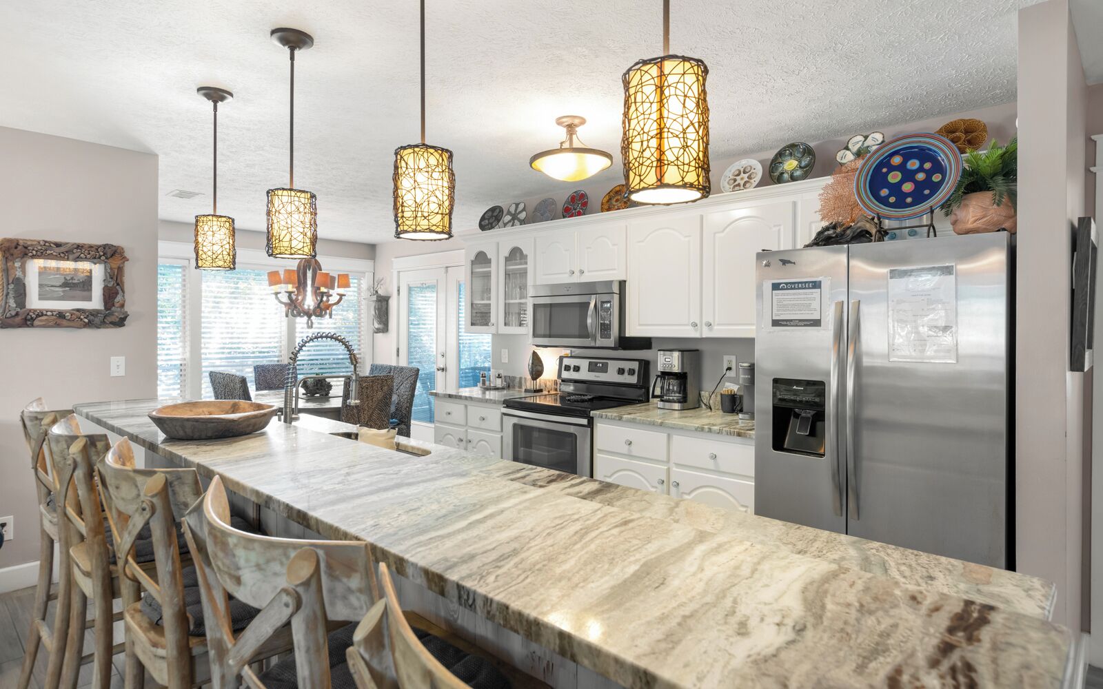 A modern kitchen with a marble countertop, stainless steel appliances, and pendant lighting.
