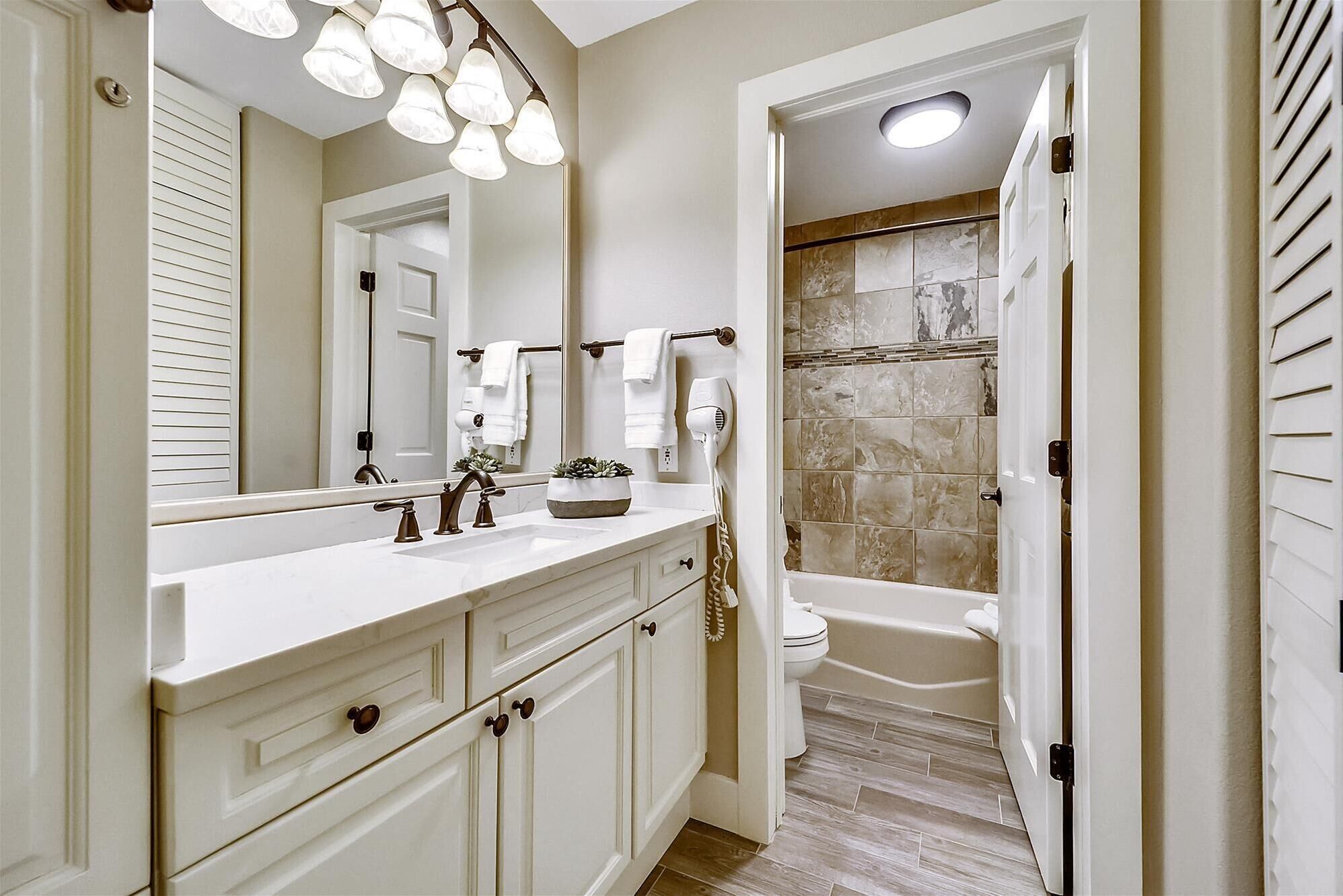 Un bagno con uno specchio grande, un mobile contenitore con cassetti, una doccia con porta in vetro e una vasca da bagno.