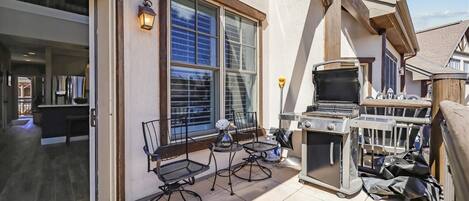Une terrasse avec un barbecue, des sièges d’extérieur et une vue sur la maison.
