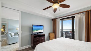 Ein Hotelzimmer mit einem großen Bett, einem Fernseher, einem Deckenventilator und Blick ins Freie.
