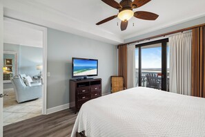 Une chambre d’hôtel avec un grand lit, une télévision, un ventilateur de plafond et une vue sur l’extérieur.