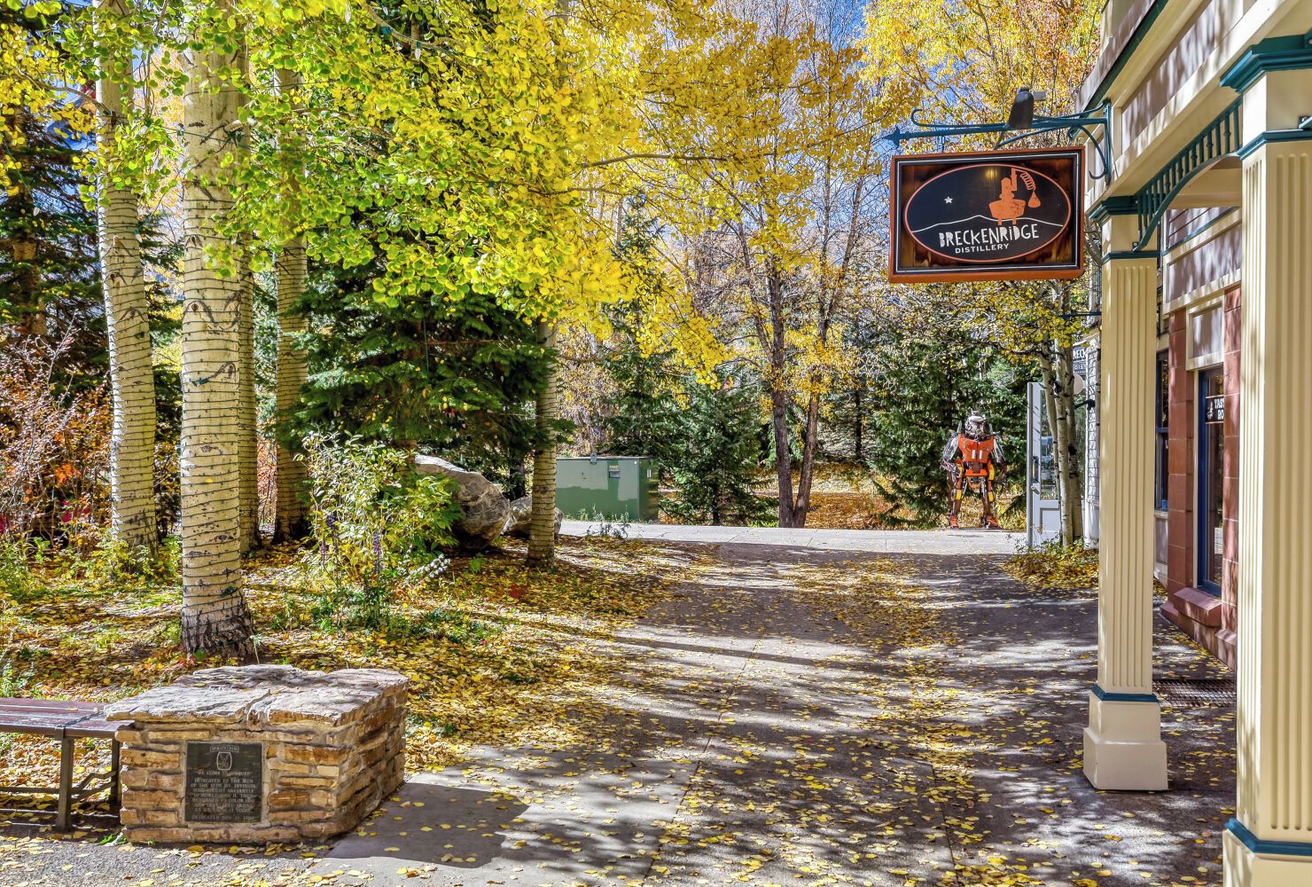 A charming autumn scene marks the entrance to this historic property, framed by golden birch trees and fallen leaves.
