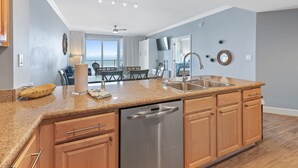 A modern kitchen with granite countertops, stainless steel appliances, and wooden cabinets. - 🌞Gulf VIEWS-BEACH Front-Pool-Grandview East 1203🌞 (Panama City Beach)
