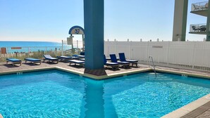 A swimming pool with lounge chairs and a view of the ocean. - 🌞Gulf VIEWS-BEACH Front-Pool-Grandview East 1203🌞 (Panama City Beach)