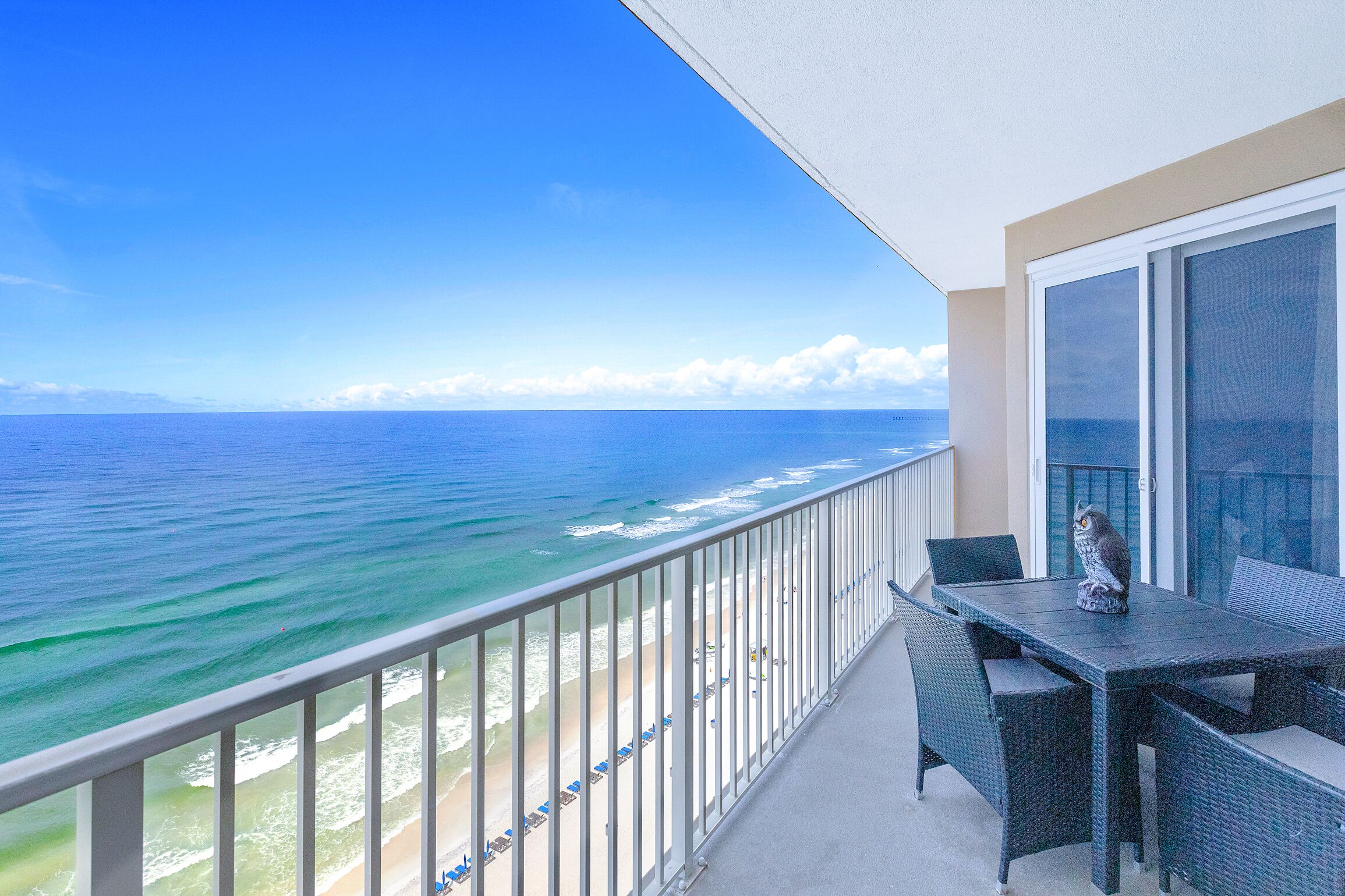 Ein Balkon mit Blick auf das Meer, einem Tisch mit Stühlen und einer Katzenstatue.