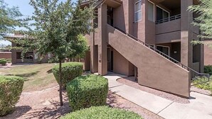A multi-story building with a central staircase, surrounded by well-maintained landscaping and trees.
