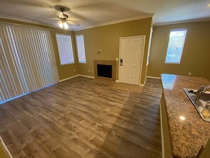 A spacious room with a fireplace, a ceiling fan, and a kitchen area with granite countertops. - Le Maisonette Spectacular- Kierland/Scottsdale (Scottsdale)