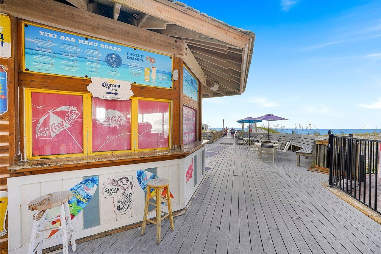 Un bar tiki con un cartel de menú, un letrero de Coca-Cola y vista al mar.