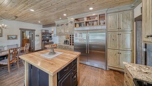 Eine Küche mit Holzausstattung, einem Edelstahlkühlschrank und einem Essbereich mit Holztisch und Stühlen.