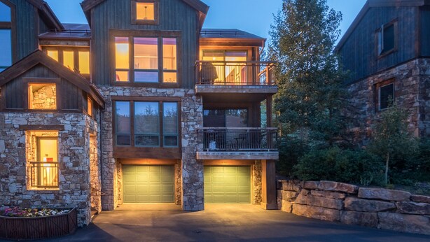 A multi-story house with a stone facade, multiple garage doors, and a balcony. - LYNX AT THE TERRACES- Slopeside Ski-In/Ski-Out Condo in the Meadows of Mountain (Mountain Village)