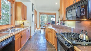 A modern kitchen with wooden cabinets, stainless steel appliances, and a large window. - LYNX AT THE TERRACES- Slopeside Ski-In/Ski-Out Condo in the Meadows of Mountain (Mountain Village)