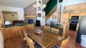 A spacious kitchen with wooden cabinets, a dining area with a large wooden table and chairs, and a stone accent wall.