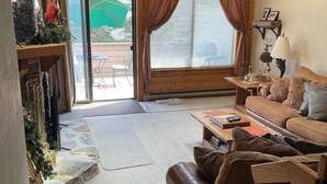 Uma sala de estar aconchegante com um sofá de couro marrom, uma mesa de centro de madeira e uma lareira de pedra.