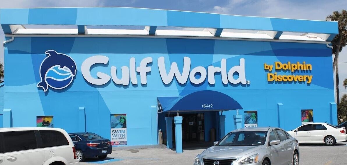 A blue building with the sign "Gulf World by Dolphin Discovery" and a dolphin logo.