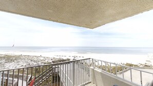 A balcony with a view of the beach and ocean.