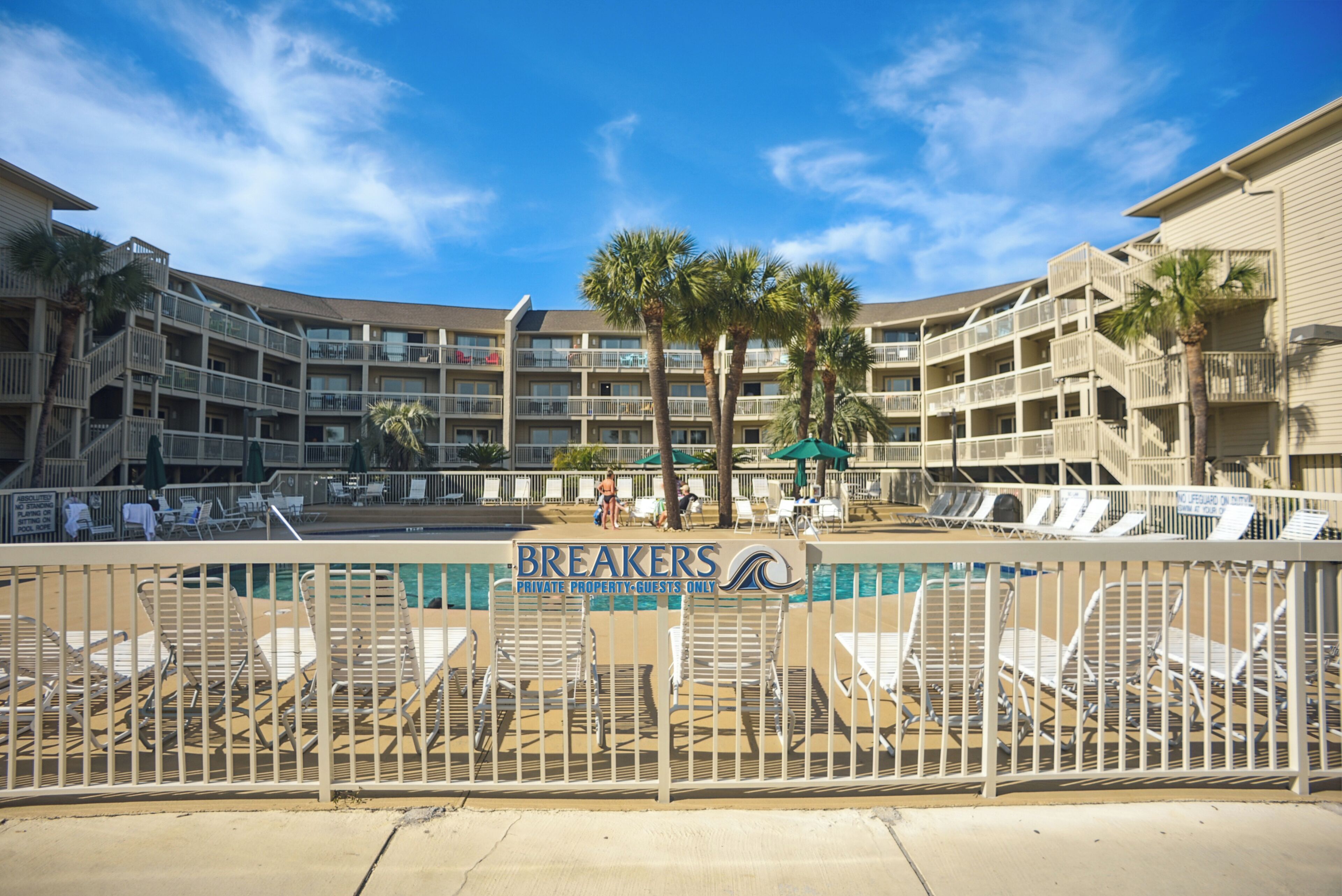 Un hôtel doté de nombreux balcons, d’une piscine et de chaises longues.