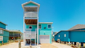 A multi-story building with a garage and a balcony. - Pet Friendly, Boardwalk, Glimpse of Ocean from Deck (Port Aransas)
