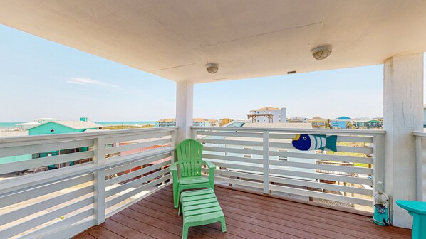 A balcony with a green chair and a decorative fish ornament. - Pet Friendly, Boardwalk, Glimpse of Ocean from Deck (Port Aransas)