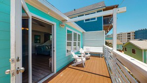 A turquoise house with a wooden deck, a balcony, and a staircase leading to an upper level. - Pet Friendly, Boardwalk, Glimpse of Ocean from Deck (Port Aransas)