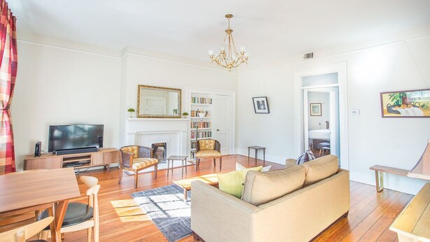 A living room with a sofa, chairs, a TV, a fireplace, and a bookshelf.