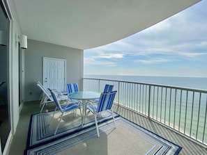 Enjoy the ocean view from this balcony with a glass table and comfortable seating.