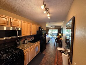 A modern kitchen with stainless steel appliances, wooden cabinets, and a dining area with a table and chairs.