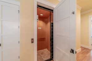 An interior view of a hallway with a white door leading to a room with a wooden door and a tiled floor.