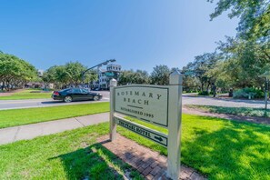 A sign for Rosemary Beach with a brick pathway and greenery.