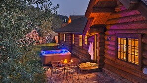 Eine Blockhütte mit Whirlpool, Sitzgelegenheiten im Freien und Steinböden.