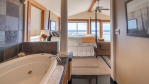 A spacious bathroom with a large bathtub, a vanity, and a view of the ocean through large windows.