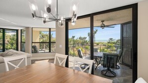 Un comedor moderno con una mesa y sillas de madera, ventanas amplias y vista al océano.