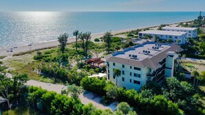 Un hotel frente al mar con varias construcciones, una playa y una vista despejada del océano.