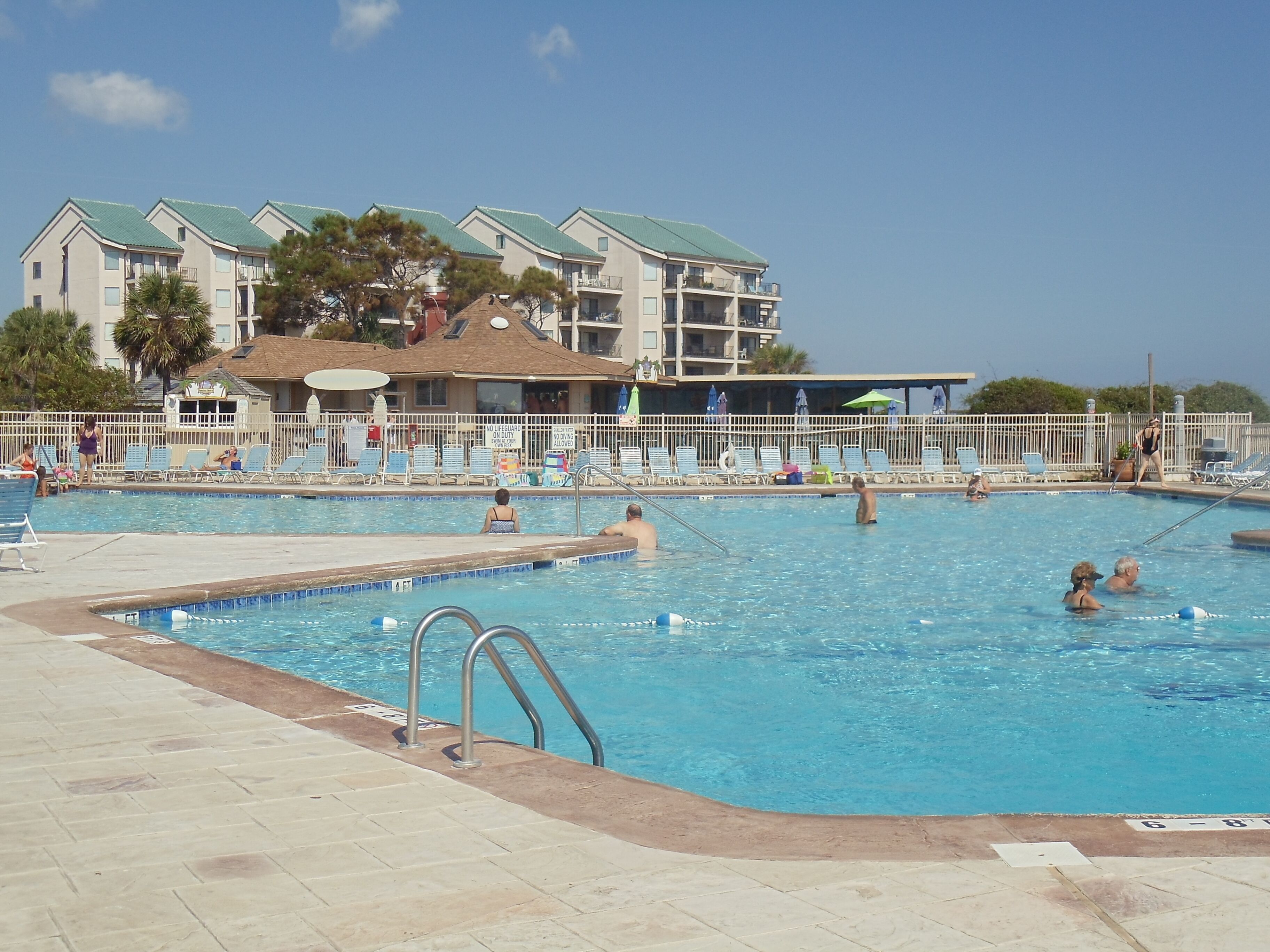 Ein Schwimmbecken mit Liegestühlen und einem Rettungsschwimmerstand.