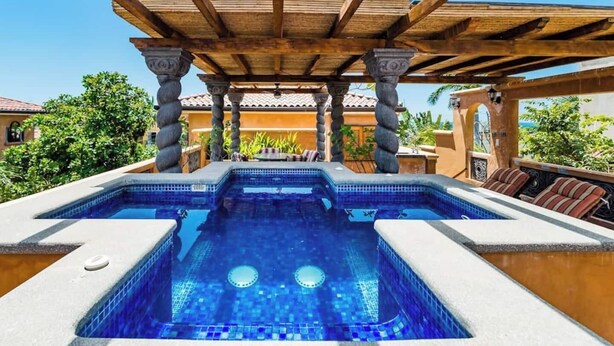 A pool area with a pergola overhead, stone columns, and a view of surrounding buildings. - Villa Buho✰Rooftop Jacuzzi & Private Pool ✰Across from Beach (Tamarindo)