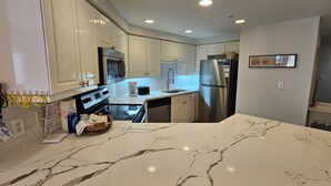 A modern kitchen with white cabinets, stainless steel appliances, and a marble countertop. - 4828 Beachfront 3BR | 16th Floor | Two Masters | Private Beach + Tram Access (Miramar Beach)
