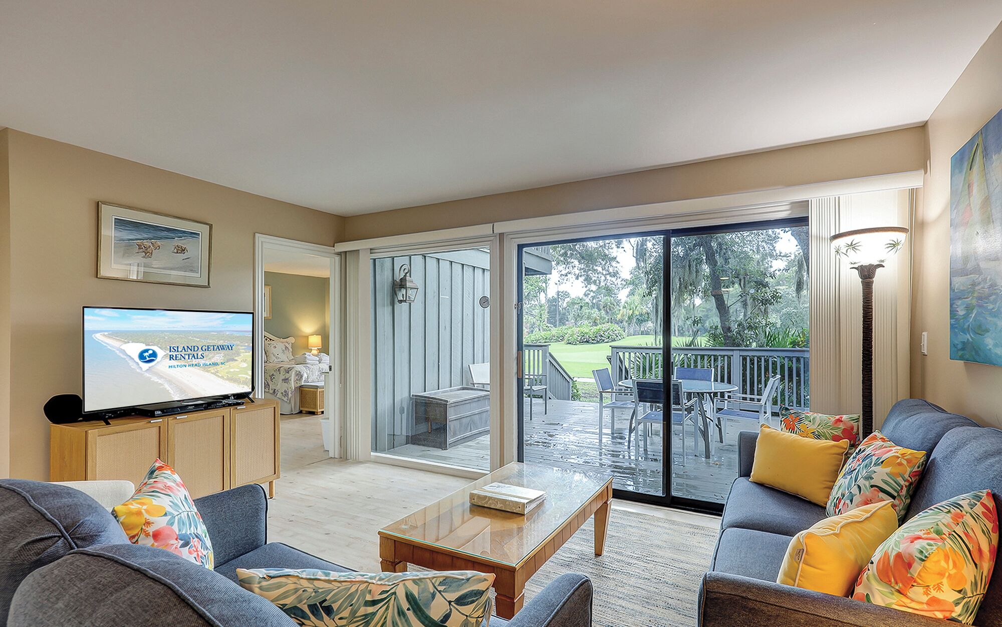 Un salón espacioso con un amplio ventanal corredera que da a una terraza, un televisor y vistas al exterior.