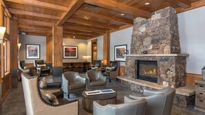 A cozy lounge area with leather sofas, a stone fireplace, and framed artwork on the walls. - ✲ Ski In / Ski Out | Zephyr Mountain Lodge 2413 | Updated Condo | Views of Divide (Winter Park)