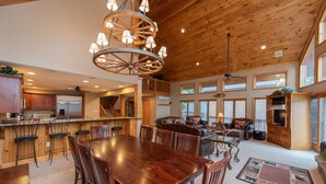 Un'ampia cucina con un grande tavolo di legno e sedie, una zona bar e un accogliente soggiorno con camino.