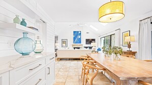 Een moderne keuken met witte kasten, een houten eettafel en een groot raam.