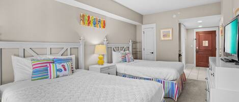 A hotel room with two beds, a ceiling fan, a TV, and a door leading to another room.