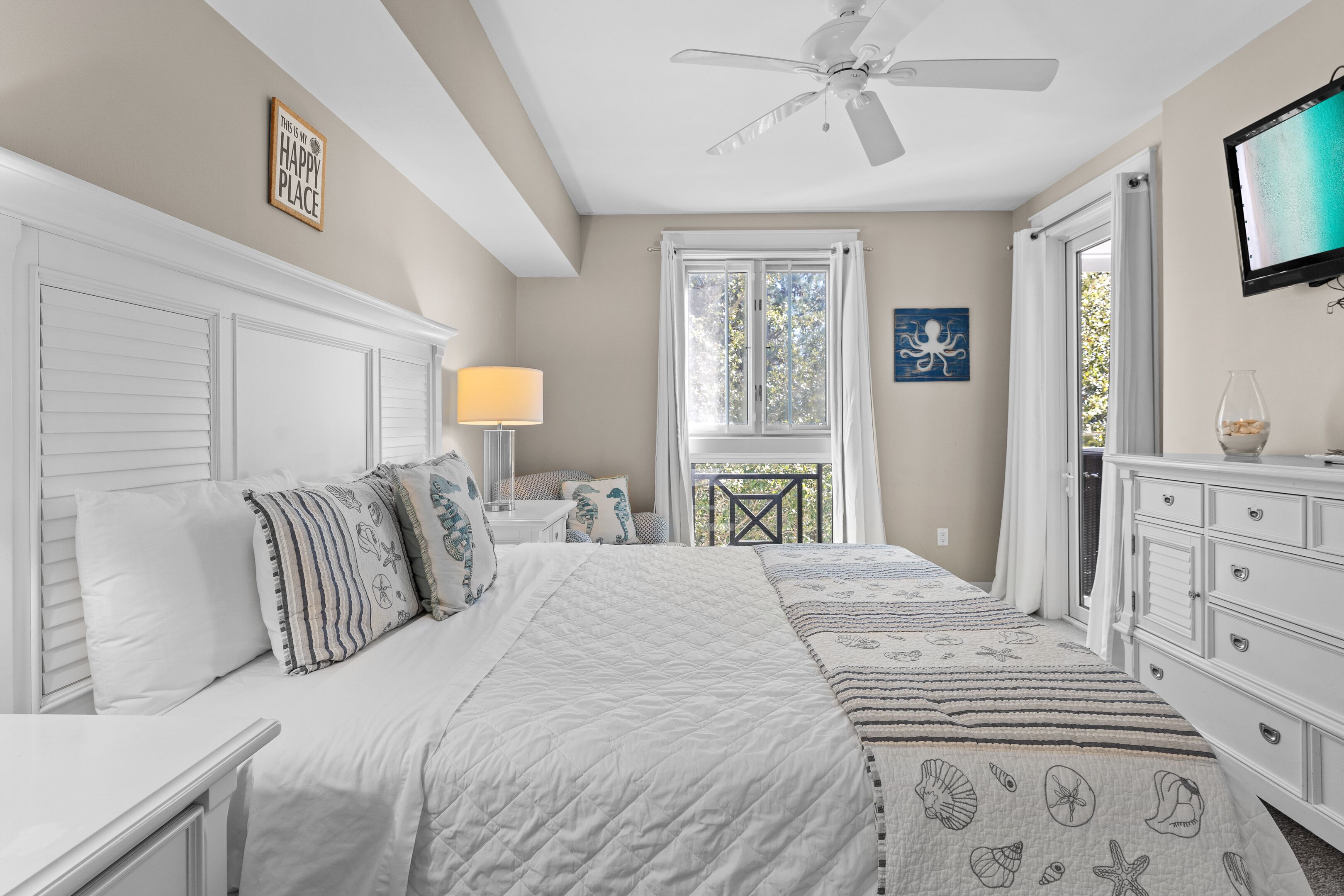 A bedroom with a bed, a nightstand, a dresser, a ceiling fan, and a window with curtains.