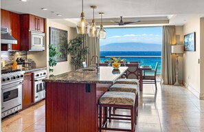 A kitchen with a central island, stainless steel appliances, and a view of the ocean.