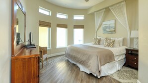 Un dormitorio con cama, escritorio, silla, ventilador de techo y ventanas.