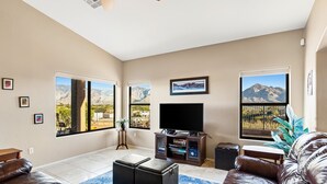 A living room with a large flat-screen TV, leather sofas, a coffee table, and a blue patterned rug.