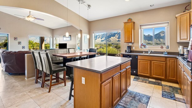A spacious kitchen with wooden cabinets, a large island, and a view of mountains through the windows.