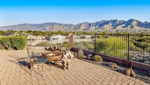 A patio with outdoor furniture, a cactus garden, and a view of mountains.