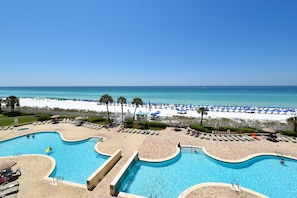 A resort with a large pool area, a beach, and a clear view of the ocean.