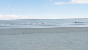 A beach with a wide sandy shore and calm ocean waves.